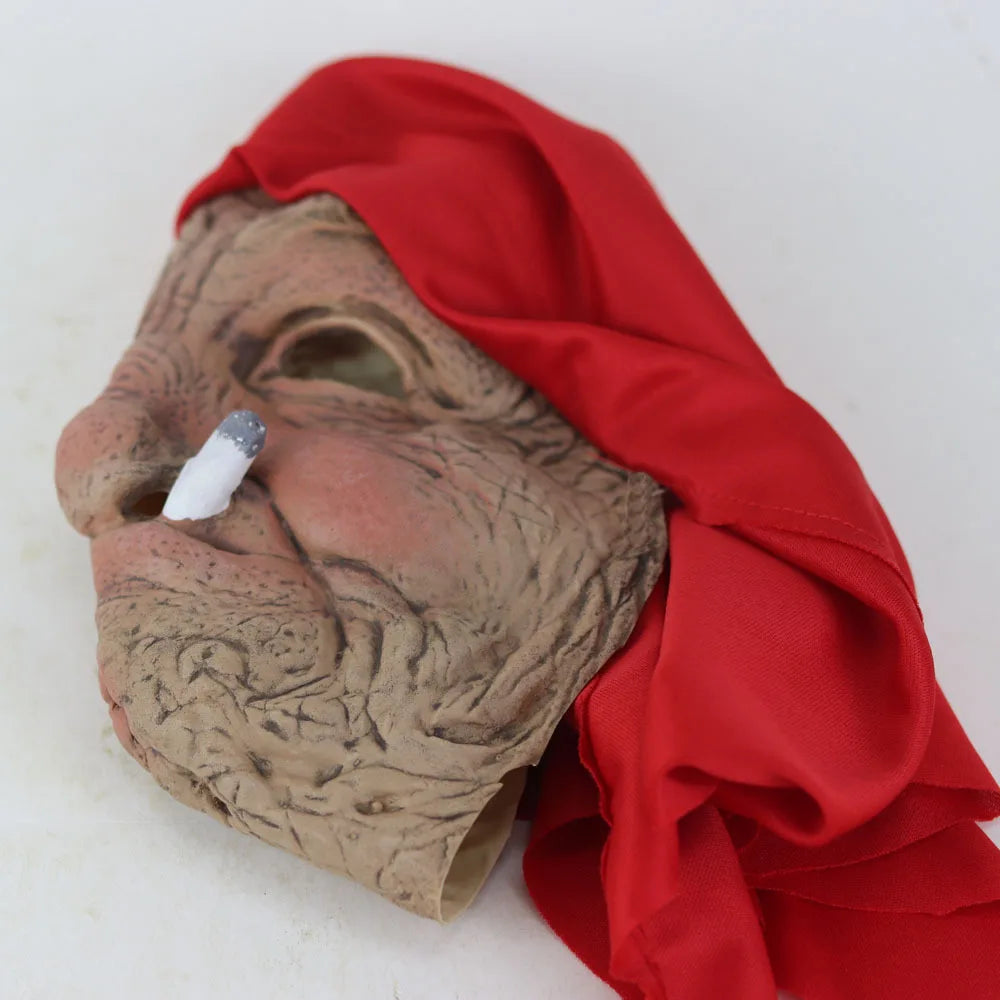 A realistic latex horror mask shaped like an elderly woman's face, covered by a flowing red fabric.
