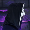 A black hooded figure wearing a white mask with visible teeth and purple accents against a purple background.