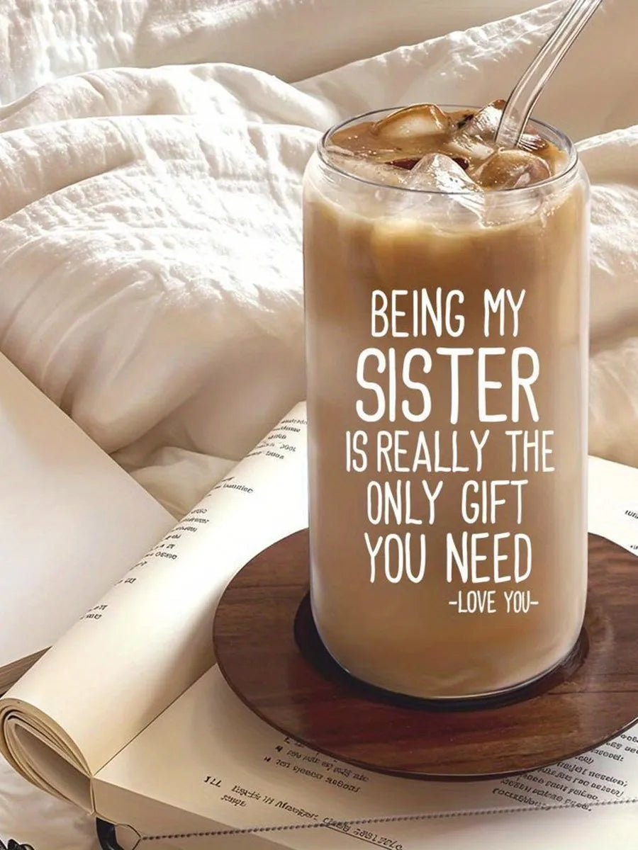 A clear tumbler filled with iced coffee sits on a wooden coaster next to a notebook.