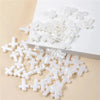 A pile of clear acrylic cross shape beads for DIY jewelry making on a white surface.