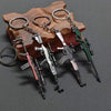 A set of realistic miniature alloy gun models on a wooden surface with metal keyrings.