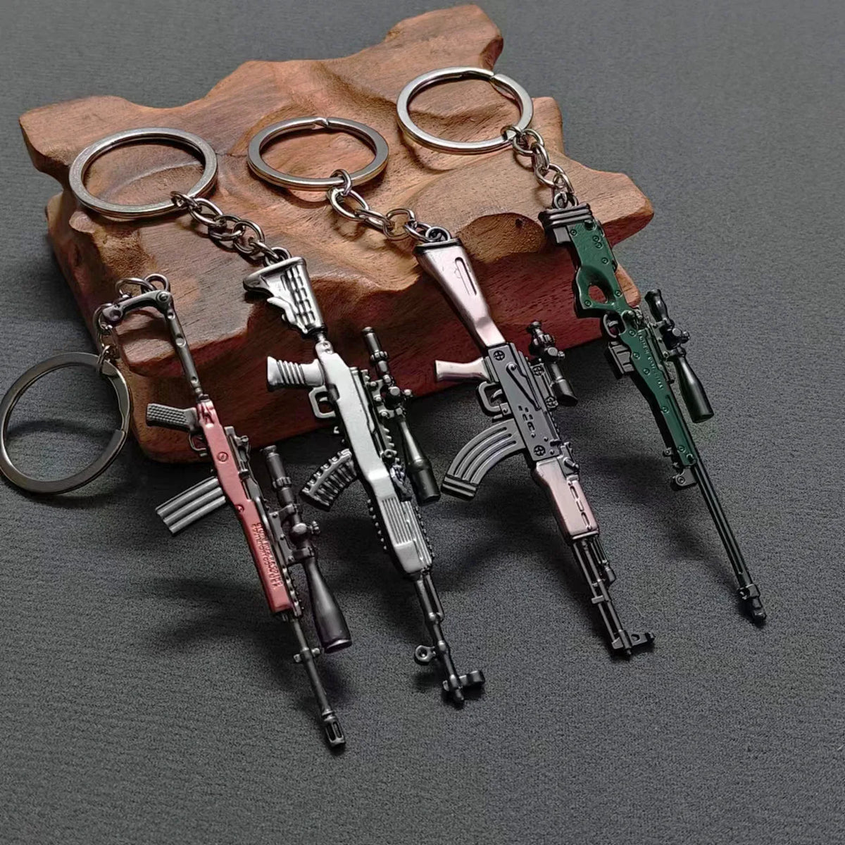 A set of realistic miniature alloy gun models on a wooden surface with metal keyrings.