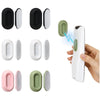 A set of magnetic silicone remote control holders in black, white, and light green colors shown alongside a hand holding a wh