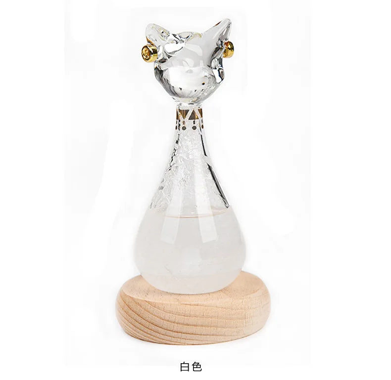 Clear glass bottle shaped like an Egyptian cat with gold accents resting on a wooden base