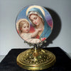 A vintage Catholic tabletop ornament featuring a painting of the Virgin Mary with a halo and a soft blue veil.