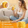 A woman is squeezing a yellow slow-rising cheese squishy toy while sitting on a couch.