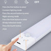 A hand presses a button on a white light fixture to cycle through different lighting modes like constant, night sensing, indu