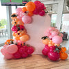 A balloon garland featuring pink and orange balloons arranged on a white background.