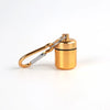 A small gold-colored pill organizer is attached to a silver keychain ring.