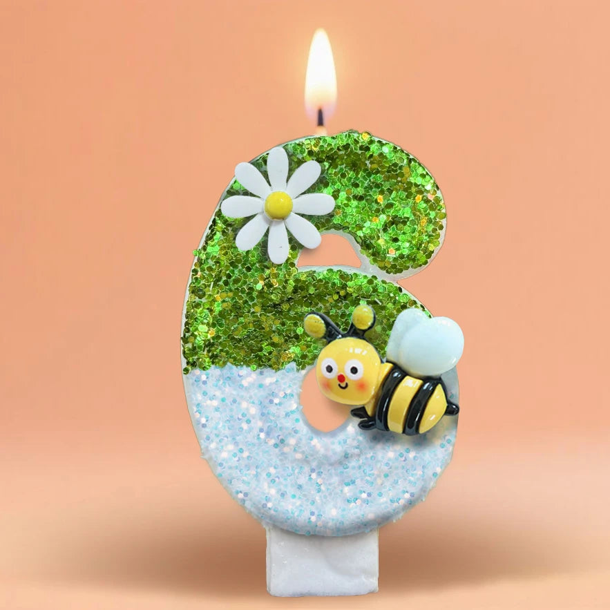 A birthday candle shaped like the number 3, decorated with green glitter and a white daisy, set against a soft orange backgro