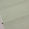 A close-up view of light green fabric with a repeating small floral pattern for sewing and quilting.