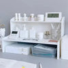 A white two-layer desktop organizer shelf displaying various stationery and desk items.