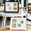 A black photo frame displaying clay paw prints and a cat's face, set on a round white table.
