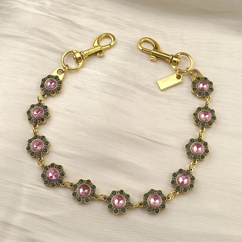 Gold chain necklace with pink and gold rhinestone flower charms and a rectangular tag.