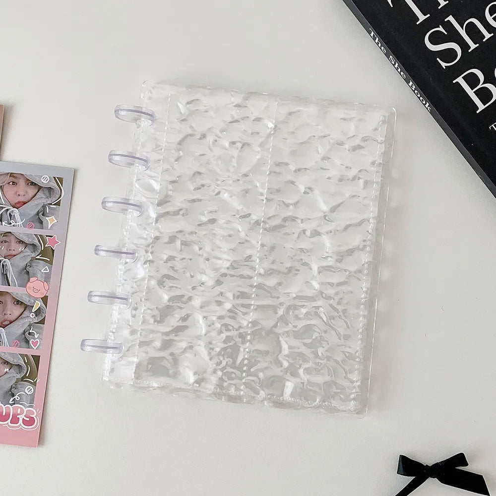 A clear transparent photocard album with a mushroom hole design resting on a white surface.