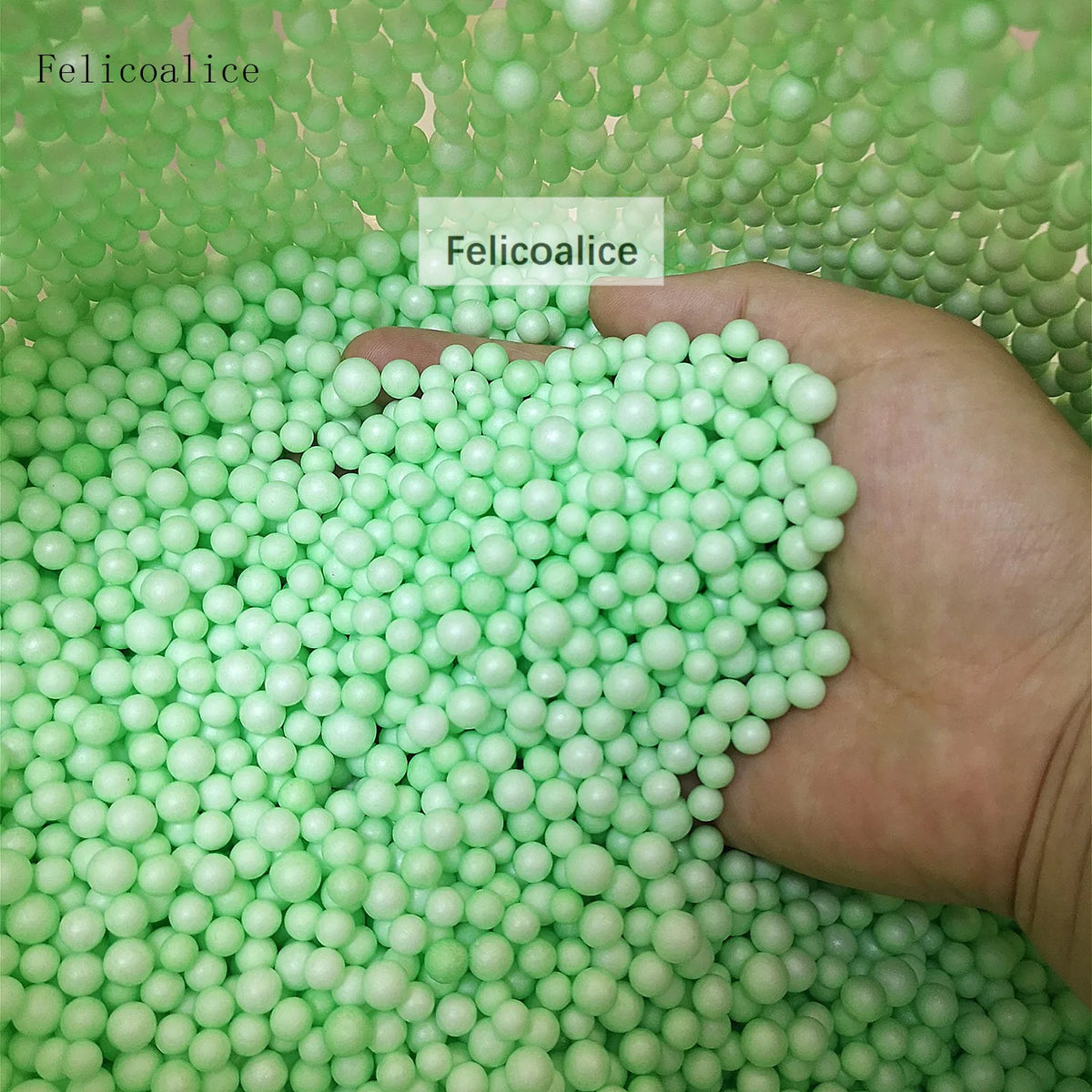 A hand holds a large quantity of light green foam beads for crafting and decoration.