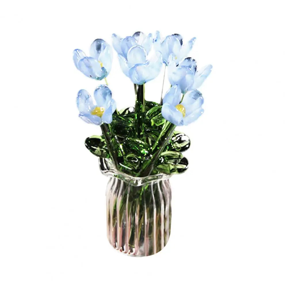 A bouquet of light blue hand-blown glass flowers in a clear glass vase.