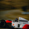 A blurred shot of a race car speeding along a track, featuring red and white livery with Shell and Honda branding.