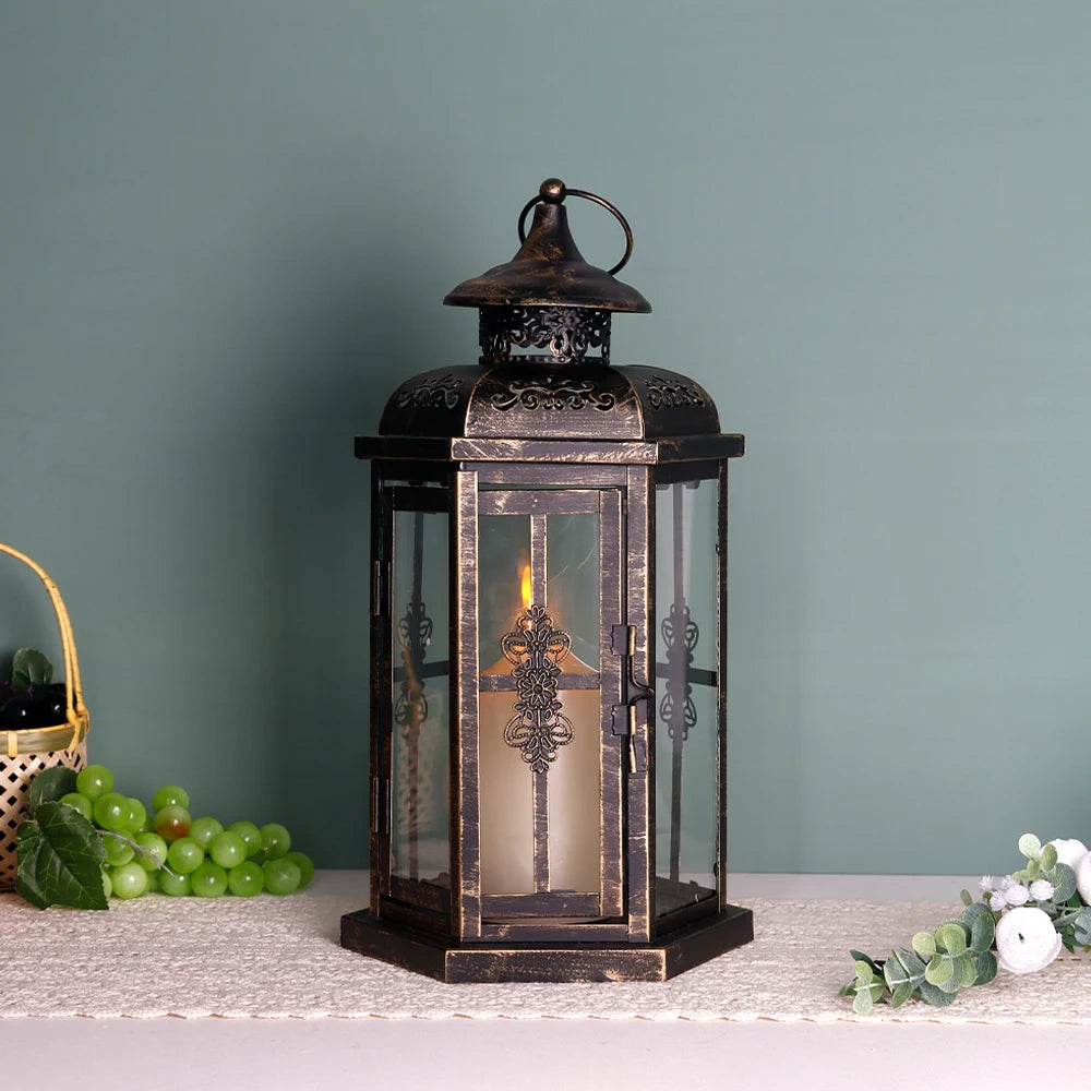 A vintage Nordic iron candle lantern with glass panes sits on a white surface next to green grapes and foliage.