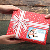 A red gift box decorated with white ribbons and a sticker featuring an arctic penguin for Merry Christmas