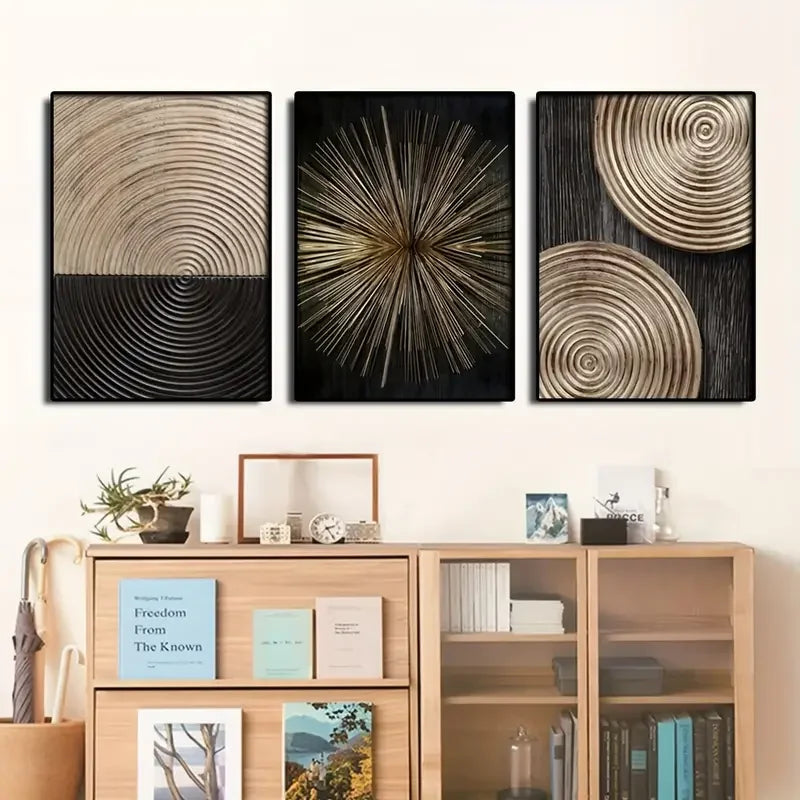 A set of three abstract canvas prints featuring concentric circle patterns in gold and black tones mounted on a wooden shelf.