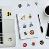 A white laptop, a spiral notebook, and various colorful graffiti art stickers are arranged on a white surface.