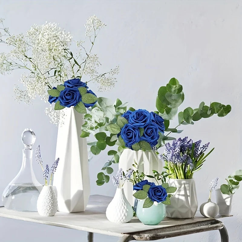 A still life arrangement featuring blue roses and greenery in white and light green ceramic vases.