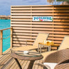 A wooden deck with a poolside sign featuring the text POOLSIDE Paradise on a metal plaque.