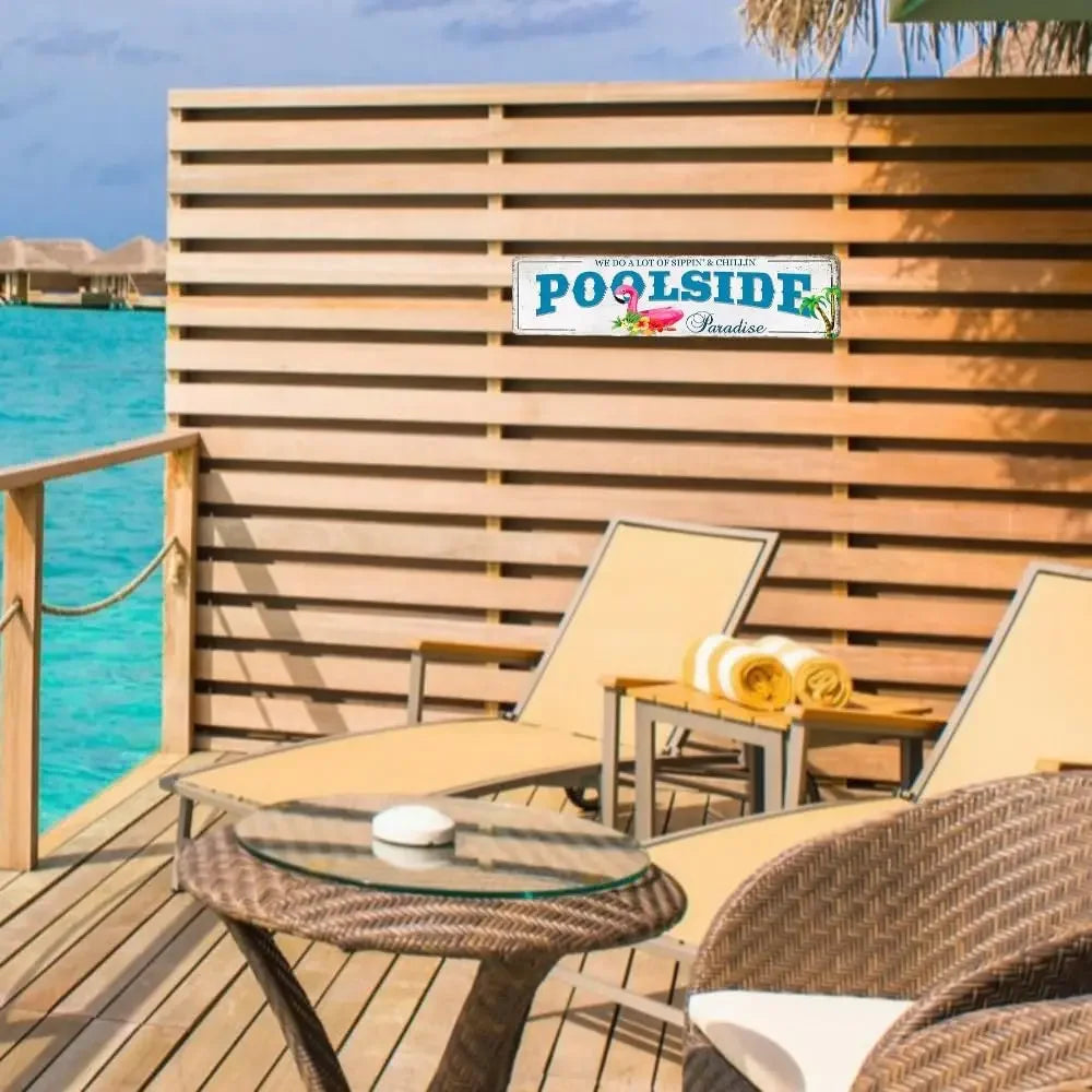A wooden deck with a poolside sign featuring the text POOLSIDE Paradise on a metal plaque.