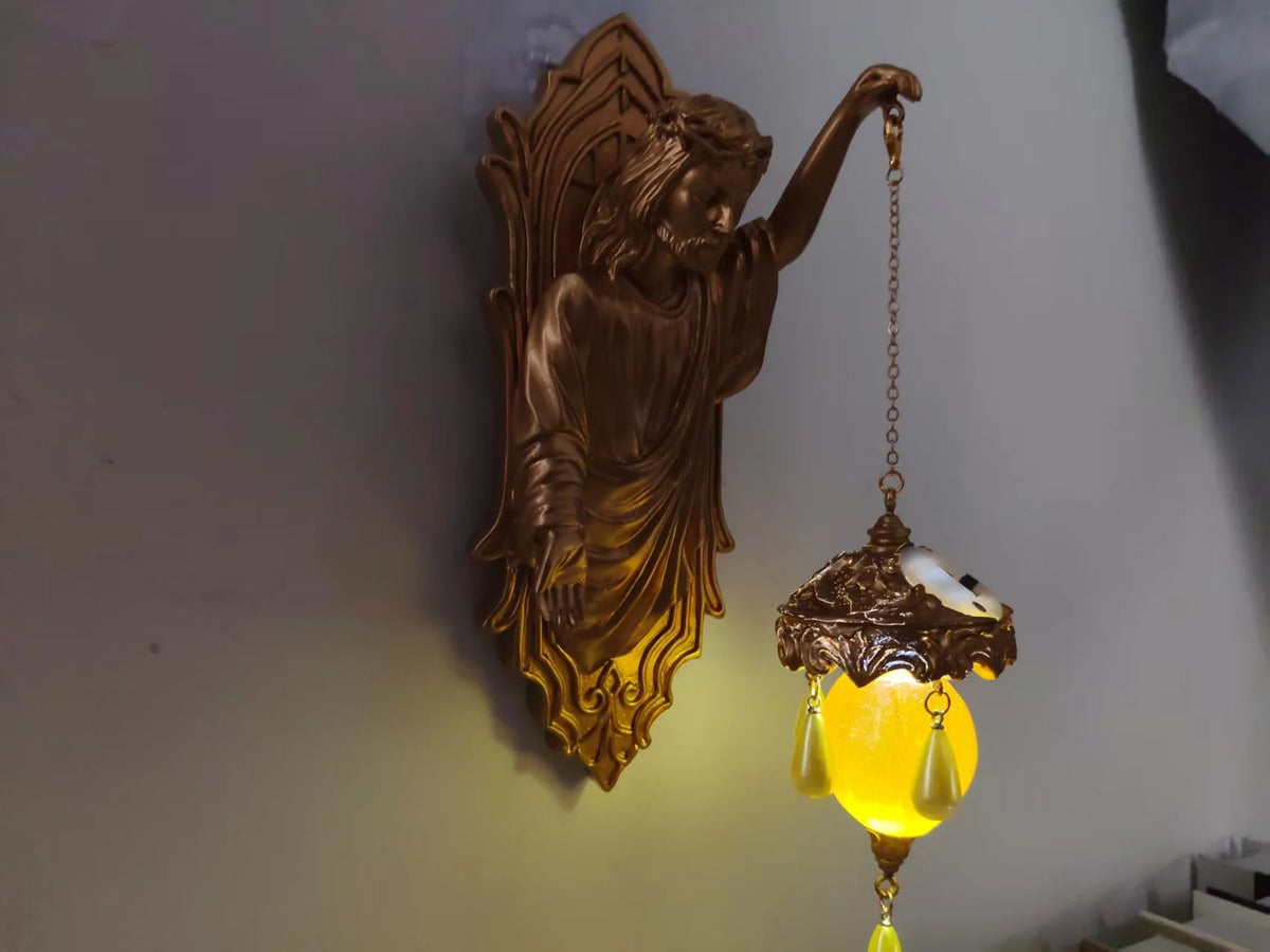 A bronze resin sculpture of a mermaid figure with flowing hair hanging from a decorative light fixture.