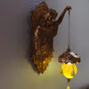 A bronze resin sculpture of a mermaid figure with flowing hair hanging from a decorative chain lamp.