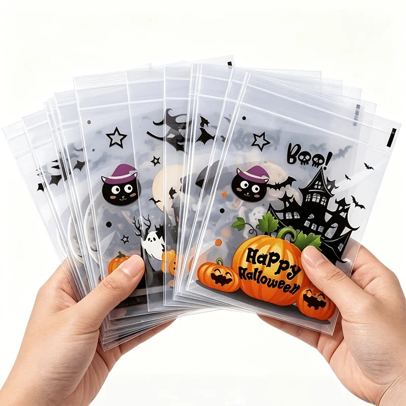 A hand holds a stack of clear self-adhesive treat bags decorated with Halloween graphics and pumpkins.