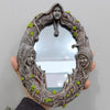 A rustic wall hanging mirror framed by branches and featuring a pentagram amulet.