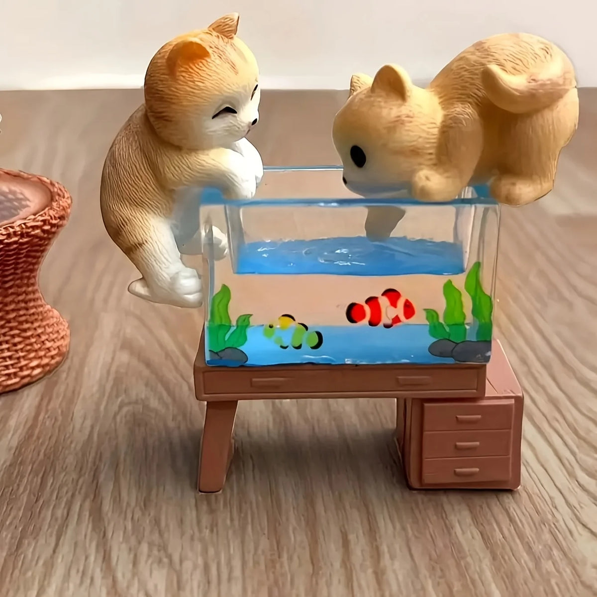 Three adorable cat figurines are displayed next to a miniature fish tank setup.