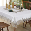 White tablecloth with floral lace trim set for a meal, featuring a bottle and gold accents.