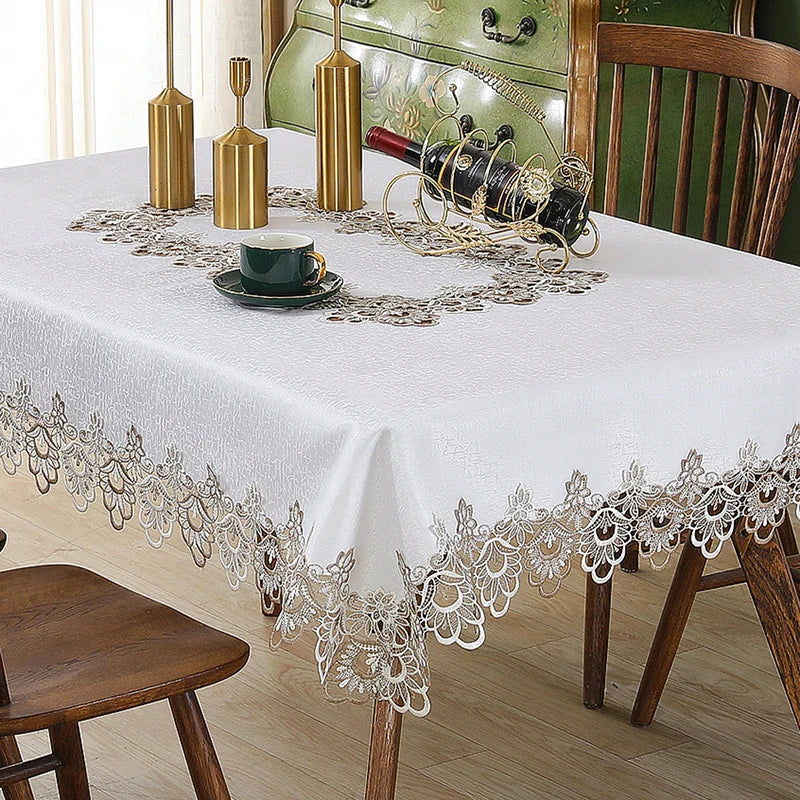 White tablecloth with floral lace trim set for a meal, featuring a bottle and gold accents.