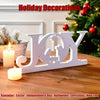 White wooden cutout letters spelling JOY for holiday decorations on a wooden table.