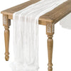 A semi-sheer white gauze table runner draped over a wooden table.