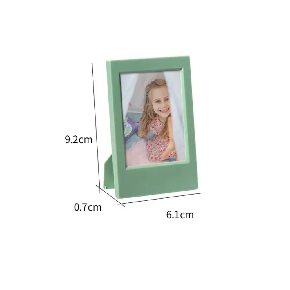 A rectangular, light green mini film frame with a glass window displaying a photo.