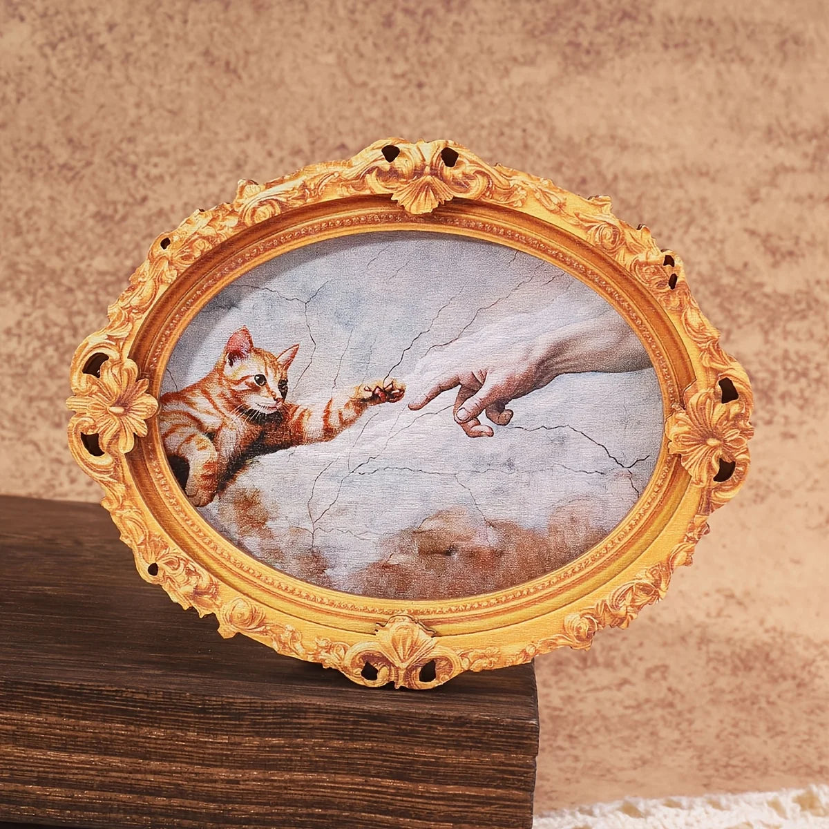 A painting of a cat paw reaching out to a human hand within an ornate gold oval frame.