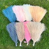 A collection of fifteen artificial pampas grass bouquets in various shades of blue, pink, white, and beige arranged on green 