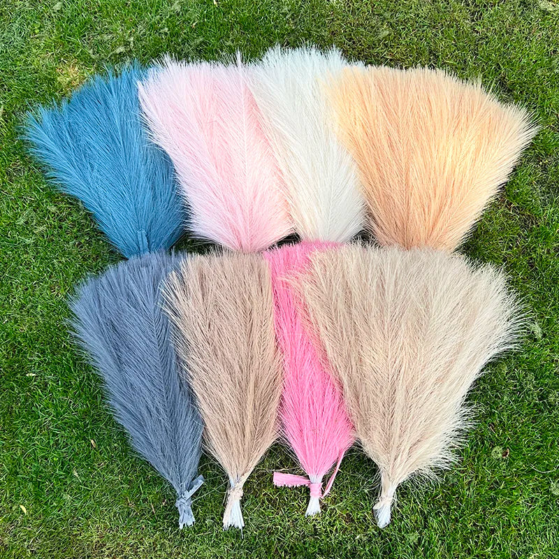 A collection of fifteen artificial pampas grass bouquets in various shades of blue, pink, white, and beige arranged on green 