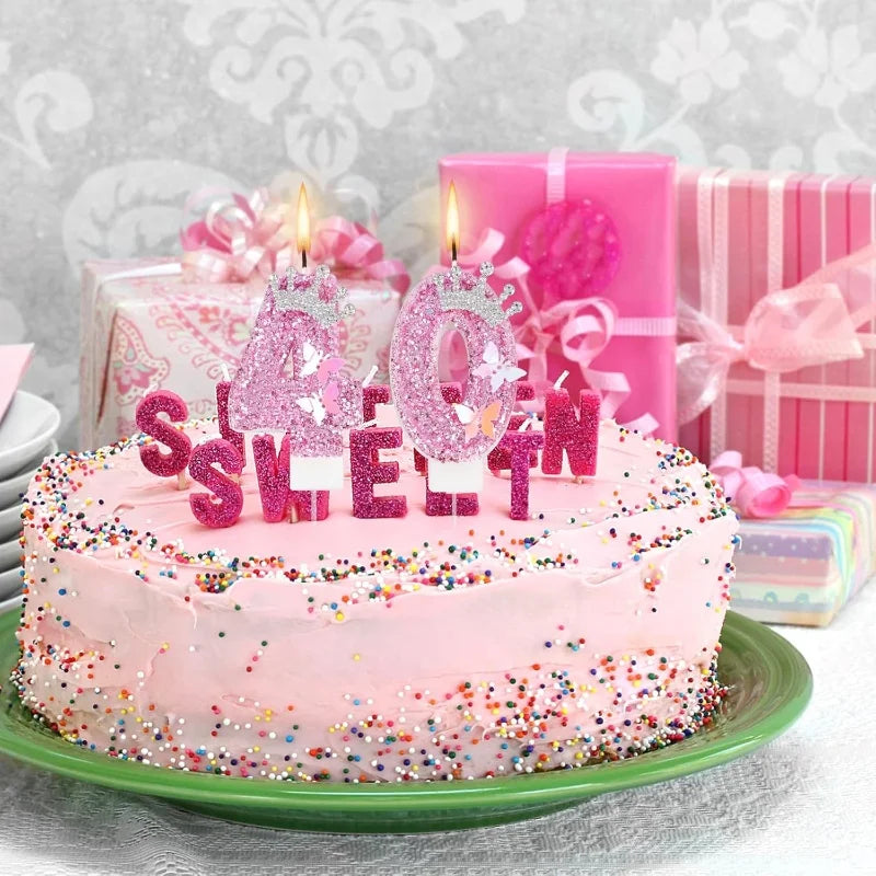 A pink birthday cake decorated with glitter and candles, surrounded by pink gift boxes.