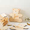 A set of wooden baby milestone cards featuring bear designs for five months and three months.