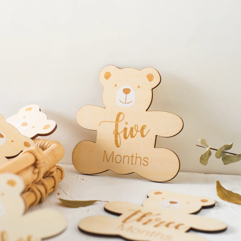 A set of wooden baby milestone cards featuring bear designs for five months and three months.
