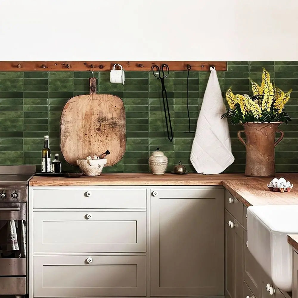 A kitchen backsplash featuring green subway tiles, wooden cutting boards, and various kitchen tools.
