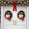 A pair of rustic wooden door wreaths featuring black felt snowmen with red scarves and green foliage, decorated with festive 
