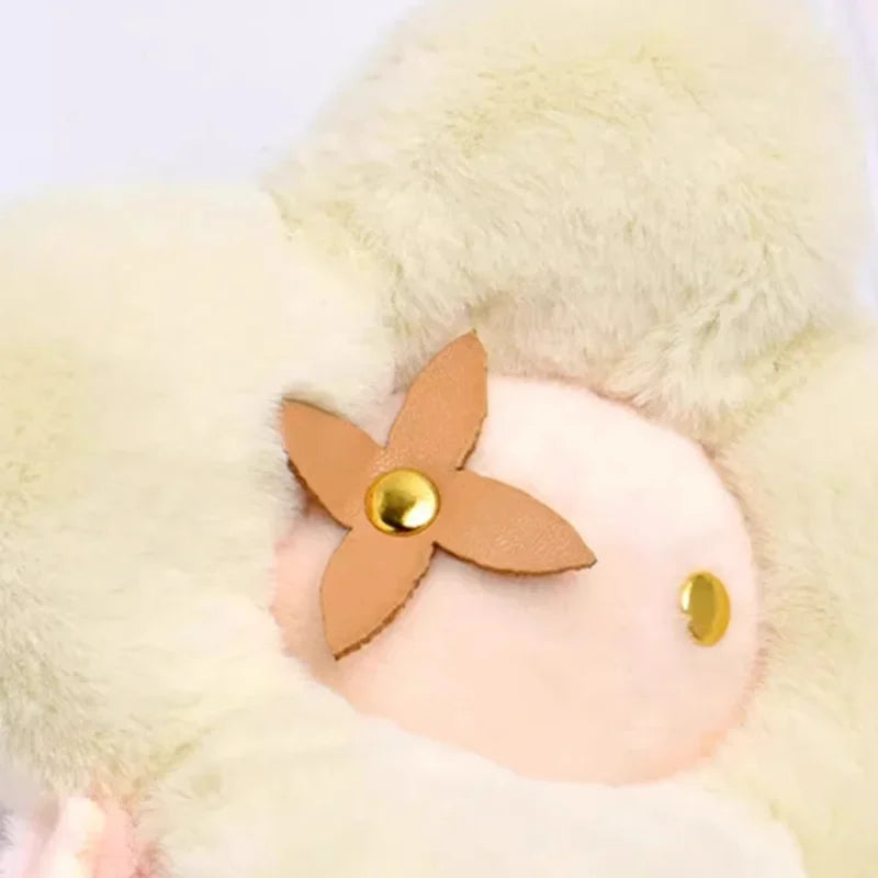 Nahaufnahme einer hellrosa Plüschdekoration in Form einer Blume mit goldenen Akzenten, umgeben von flauschigem cremefarbenem 