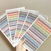A hand holds several sheets of glitter gem stick-on facial tattoos displaying a wide variety of colorful gems.