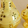A close-up of a gold-plated Orthodox censer with bells, showing its ornate design and texture.